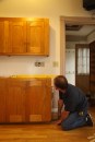 Donbeck sets the cabinet temporarily, checking front and back for level and looking for bows in the floor.