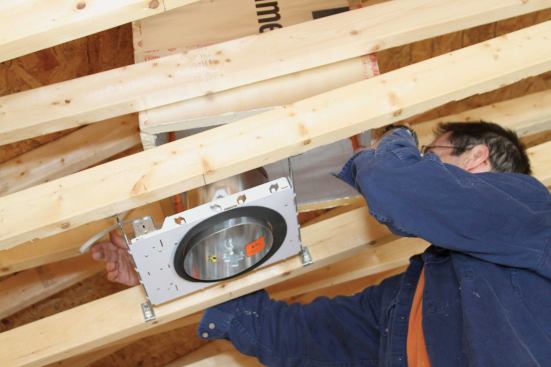 Recessed lights in a cathedral ceiling must be addressed before the lid is hung. Here, the author surrounds a fixture with a box made of foil-faced foam.