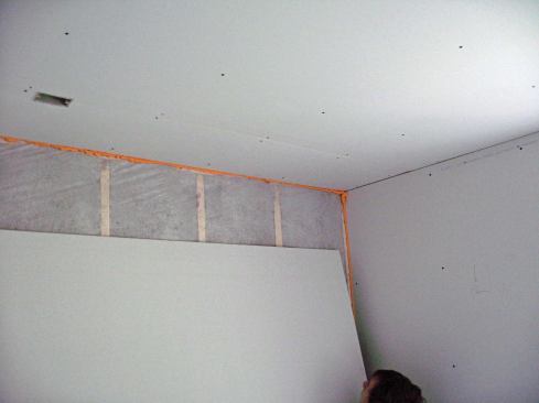 To seal the drywall perimeter, a helper applying sealant needs to stay in front of the crew hanging the panels. 