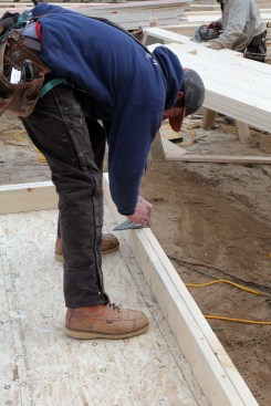 The layout crew member then draws a square line across the plates for the other side of the rough opening of the side window.