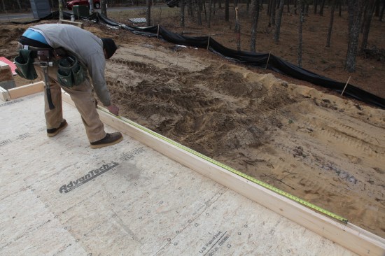 With the measuring tape hooked on the nail, the studs are marked out along the plate—this time with the layout crew marking directly on the highlighted tape measurements instead of deducting 3/4 inch.