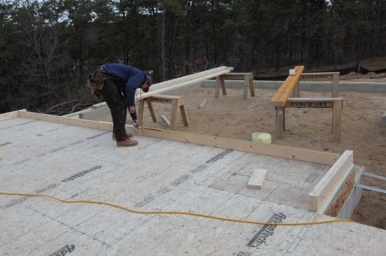 Next, a measurement is taken from the end of each board to the overlap to obtain the lengths for the boards that will fill in the rest of the top and bottom plates. Those boards are then cut and tacked in place.