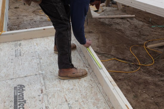 After marking the stud pocket (the doubled stud between the windows), the crew member measures over for the rough opening of the side window.