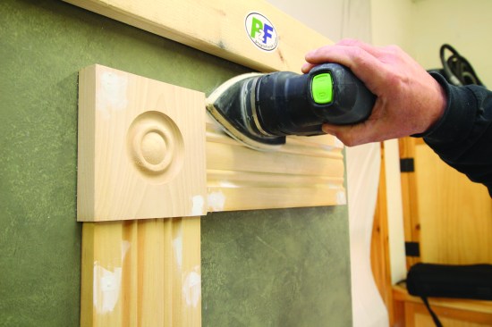 Sanding with machines allows the addition of a dust-collection system. Here, a sander with a flat sanding pad works on a filled hole.