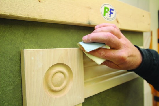 Slightly breaking the sharp edges of the trim helps with paint adhesion, and hand sanding is best for this task.
