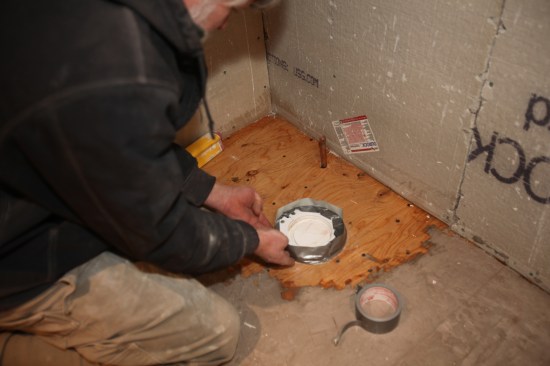 The liquid leveler will seep through any opening, so every gap must be filled. Here duct tape is applied as a dam around the toilet flange.