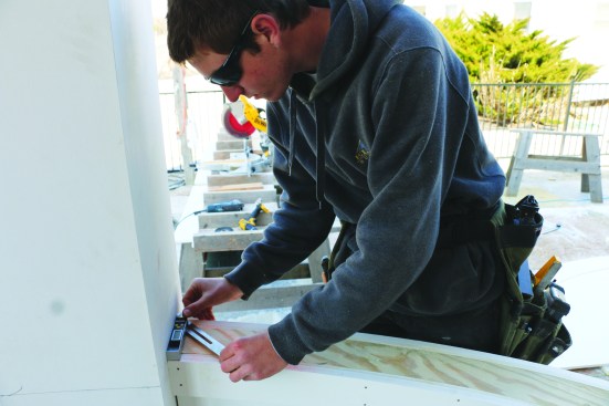 Having snapped the same line on top of the knee wall, a crew member measures the angle between the snapped line and the post.