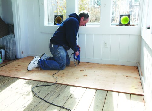 The author installs 1/2-inch plywood to reinforce the existing floor, then covers it with a layer of modified thinset.