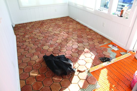 All cuts are made with a wet saw. Switching to a shorter straightedge, he works his way back across the room.