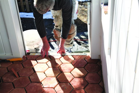 A short strip of wood aligns the last tiles at the entry door. A threshold will be installed later to protect the tile at the entry.