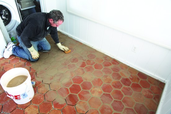 When the grout has set, he wipes the floor down twice with a sponge and water, starting with a fresh bucket of clean water each time. Because of the rough finish on the terra-cotta tiles, he doesn’t try to remove all of the grout haze at this point.