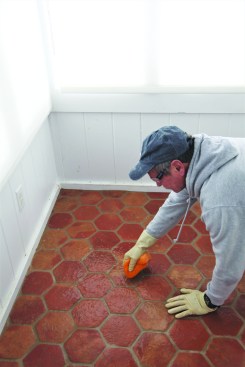 Working with the acid solution in a small area, he thoroughly soaks the tile with fresh clean water, letting the water puddle on the tile to neutralize any residual acid before he soaks up the solution and wipes off the tile with a clean sponge. He later returned and sealed the whole floor.