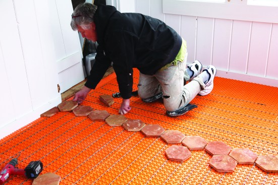 A crew member does a dry layout across the floor, adjusting the grout joints for an even layout.