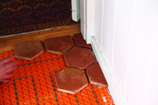 To set the starting point for the installation, he scribes the tiles that will be installed at the main doorway into the house.
