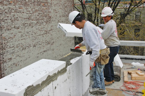 Parapet walls for low-slope roofs can be insulated with a rigid-foam wrap that integrates into the wall insulation and the roof insulation of the building, as shown here in a Passive House project from 2016.