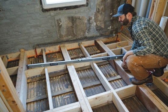 Co-author Chris Hovious checks the framing for flatness after leveling an existing floor for a bathroom remodel. New framing and sistered 2-by stock was added to support the existing joists and help stiffen the floor.
