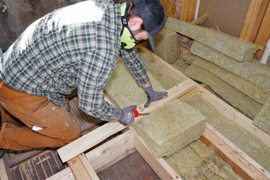 Hovious cuts Rockwool insulation to fit a cavity (above)…