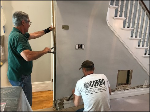 The author (standing) and project manager Danny DoCouto surgically remove trim on the wall separating the living room and kitchen from the basement stairwell.