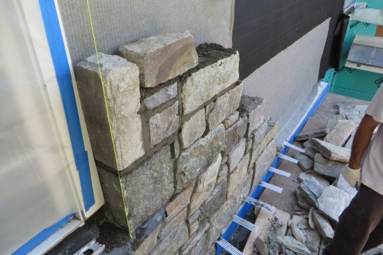 The exposed face of coated copper flashing was protected with blue tape, then the water management layers were installed on the wall.