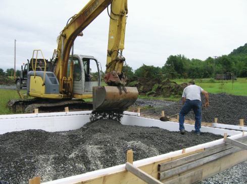 Because the outbuilding that would top the slab would be heated, we placed 2 inches of rigid insulation over compacted mixed stone with fines before pouring the concrete.