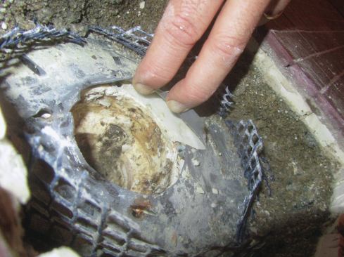 Further digging revealed a third problem: The shower liner material was not properly glued to the drain body. Someone had tried to use silicone caulk, which in our experience is not a long-term solution for water sealing. Predictably, it had failed.