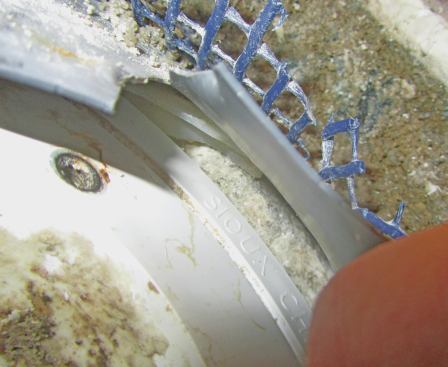 The silicone molded to the drain body below, which helped us find a fourth big problem: The clamp ring and drain body were from two different manufacturers and didn't seal properly. The words "Sioux Chief" (siouxchief.com) were molded into the silicone pieces we pulled out. Sioux Chief drains have a slot on top of the drain body, and the smooth clamp ring has a molded bump that presses the liner down into the slot.