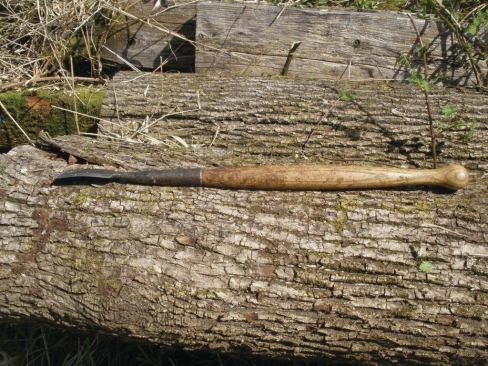 A peeling spud has a steel blade about 6 inches long and about 2 1/2 inches wide mounted on long wood handle. The blade is slightly curved and sharpened on the end as well as on both sides.