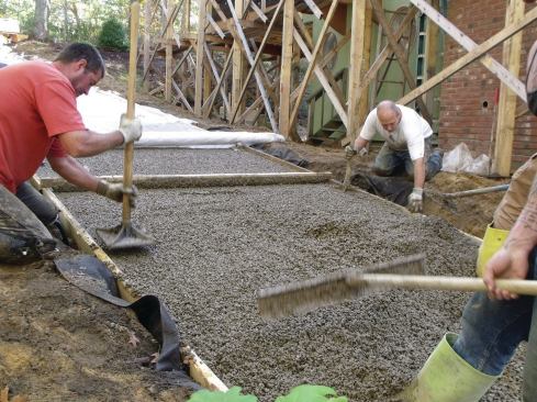 While the machine was being refilled, crew members compacted the edges and screeded the surface flat with a straightedge. 
