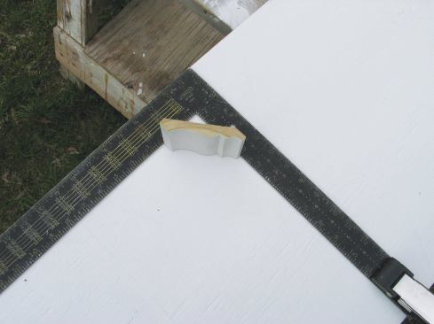 To make a full-size drawing, I clamp a framing square to a sheet of plywood and scribe along both legs: one line for the ceiling and the other for the wall. I place a piece of the crown against both legs, tight inside the square. Then I scribe all the way around the molding.