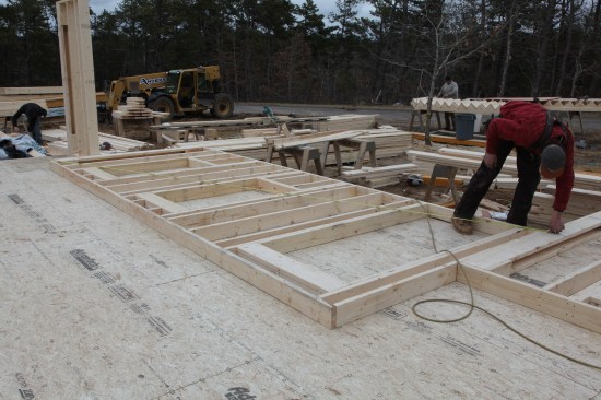To square the wall framing, a crew member takes diagonal measurements from corner to corner and adjusts the wall until those measurements match precisely.