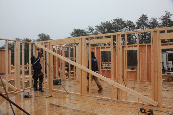 The bearing wall has no sheathing, so a diagonal brace is nailed on from corner to corner in order to hold the wall square and plumb.
