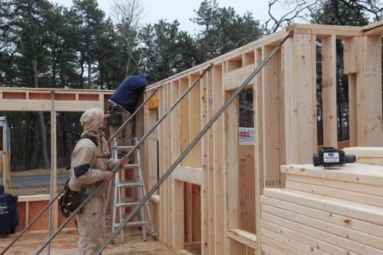 After the framing and sheathing has been completed on the walls, the crew straightens the walls. One person sights down the top plate and another turns the braces to make micro-adjustments until it is perfectly straight.
