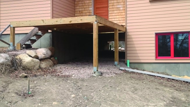 The garage sits on its own independent foundation, and the elevated mudroom entry between the garage and the house provides a clear path underneath for running piping from the back of the house to the front, where water can drain away safely.