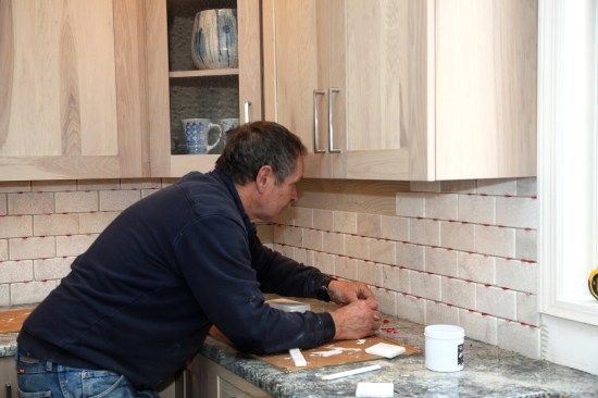 The installation continues from that first course of tile up and toward the corner. 