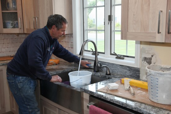 The mosaic tile also adds a decorative touch behind the sink and under the window. Again the author uses a rubber trowel to bed and flatten the mosaics.
