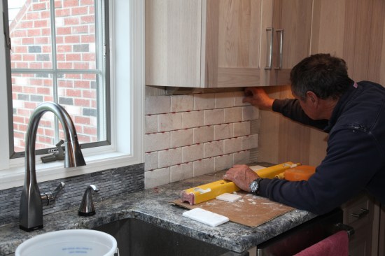 The author then works from the other side of the window over to the corner to complete the backsplash tile.