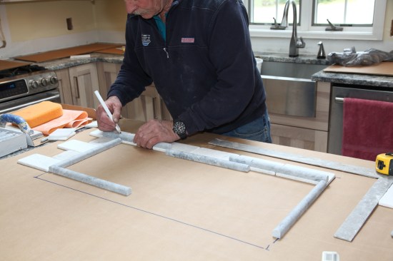 To make the installation go more smoothly, author makes a dry layout of the mosaic mural ahead of time on a sheet of cardboard. Here he marks the bull-nose border before cutting the mitered corners.