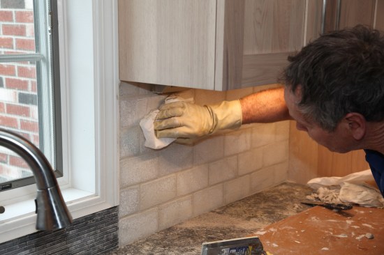 After the grout begins to set up, the author uses a dry paper towel to make the first wipe. He purposefully does not add water at this point, because too much water can weaken the grout.