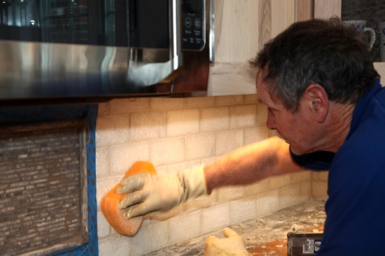 While the grout on the mosaics sets up, a damp sponge continues to clean the surface of the field tile. 