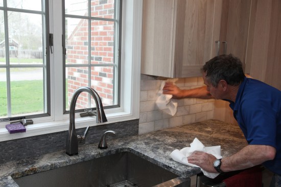 When all the tile has been grouted, the author removes the final grout haze with paper towels. Even when stone tile has been presealed, a final wash with grout cleaner may be necessary to clean the last of the grout off the stone. The author finishes the job with a coat of sealer on both the tile and the grout, and the kitchen is ready for the chef. 