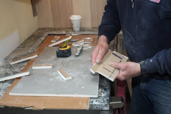With this remodel, the receptacles over the counter were removed and placed under the wall cabinets. To fill the leftover holes, the author scores patches of drywall and peels off all but the outer layer of paper around each patch.