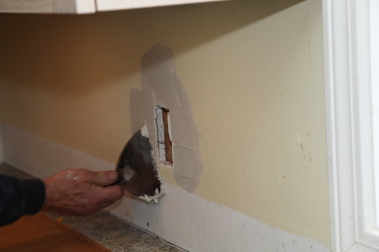 The author applies thinset to the drywall around the opening before pressing the patch into place. The tile installation can proceed without waiting for the thinset to dry. 