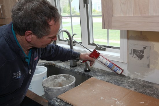Behind the sink, a bead of silicone seals the seam between the tile and the countertop.