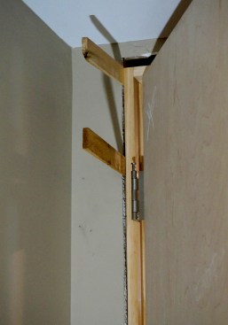 Snug a shim into the gap between the jamb and the framing just above the top hinge.