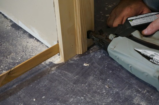 On the latch side, insert a shim at the bottom of the jamb and secure it with a nail driven just above the shim.