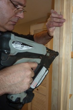 When the reveal between the door slab and the jambs is perfectly even, go back and secure the jambs at each shim with two nails driven through the shims this time.