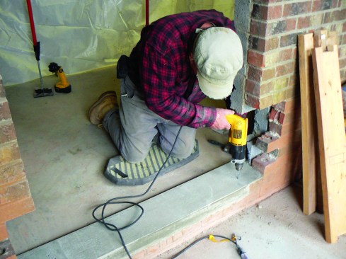 To anchor jambs to the sill, he first drills holes.