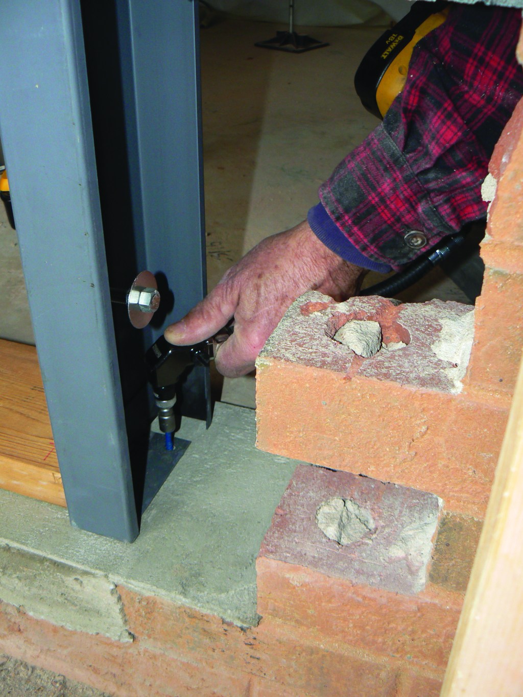 Then he drives Tapcon concrete anchors into the holes with a flexible drill.