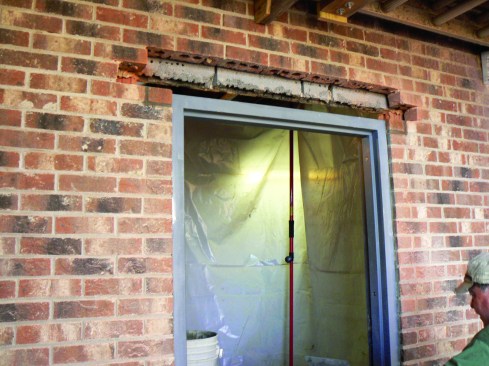 Bricks at the top corners of the frame bring the masonry to a height 1/2 inch above the header jamb.