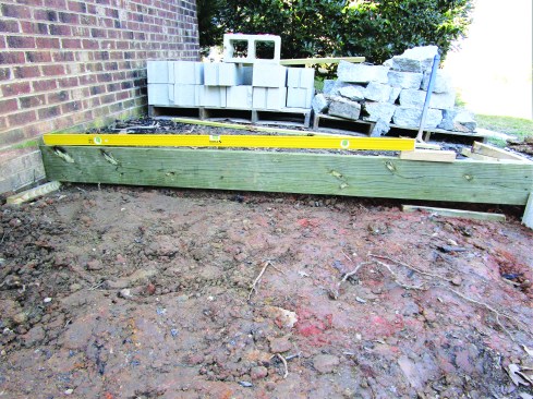 From the porch floor, the crew measured down 66 1/4 inches (6 5/8 inches multiplied by 10 risers) and marked a base line for the 6-inch-thick slab. They set the 1/4-inchper- foot slope of the base by placing a 6-foot level on the form board with one end of the level sitting on a 2-by block to create the proper slope.